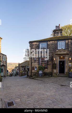 Haworth Dorf, wo Bronte Schwestern lebten, steilen, malerischen, engen Main Street View, Black Bull Pub im Vordergrund - West Yorkshire, England, UK. Stockfoto