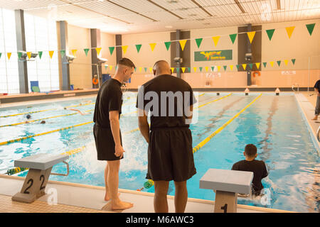 Us-Soldaten beobachten, wie der US-Armee Garnison Benelux Wettbewerber im Swimmingpool, der während der Garnison besten Krieger Wettbewerb beim Obersten Hauptquartier der Alliierten Mächte Europa, Belgien, Feb.21, 2018 springen. (U.S. Armee Stockfoto