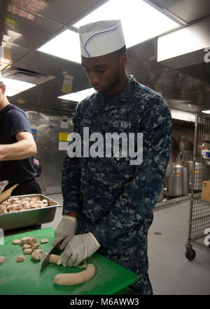 NEWPORT NEWS, Virginia (Feb. 22, 2018) Kulinarische Specialist Seaman Marvin Chapman, aus Baltimore, schneidet Wurst. Der Nimitz-Klasse Flugzeugträger USS George Washington (CVN 73) befindet sich in einem Tank- und komplexen Überholung (RCOH) bei Newport News Werft. RCOH ist ein fast 4-jährigen Projekt nur einmal während einer Fluggesellschaft, die 50-jährige Nutzungsdauer, einschließlich Betankung von zwei nukleare Reaktoren des Schiffes sowie erhebliche Reparaturen, Upgrades und Modernisierung. (U.S. Marine Stockfoto