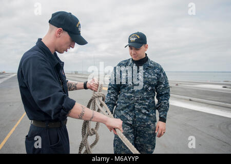 NORFOLK, Va (Feb. 22, 2018) der Bootsmann Mate Seemann Anthony Cline lehrt Airman Andy Morales wie ein Knoten an Bord der Flugzeugträger USS George H.W. zu binden Bush (CVN 77). Das Schiff ist im Hafen in Norfolk, Virginia, die Durchführung von routinemäßigen Wartung in Vorbereitung für den Vorstand der Überprüfung und Besichtigung (INSURV). (U.S. Marine Stockfoto