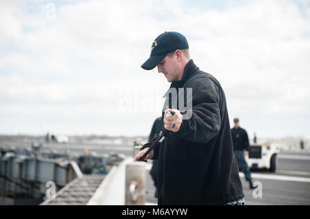 NORFOLK, Va (Feb. 22, 2018) der Luftfahrt Bootsmann Mate (Handling) 3. Klasse Tristan De Young führt einen Safety Line durch eine Haltestange an Bord der Flugzeugträger USS George H.W. Bush (CVN 77). Das Schiff ist im Hafen in Norfolk, Virginia, die Durchführung von routinemäßigen Wartung in Vorbereitung für den Vorstand der Überprüfung und Besichtigung (INSURV). (U.S. Marine Stockfoto