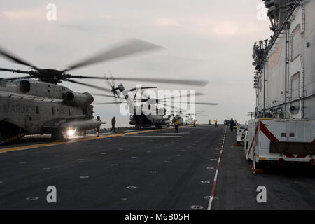 Golf von Thailand (Feb. 23, 2018) CH-53E Super Hengste, das "WOLFPACK" der Marine schweren Helikopter Squadron (HMH) 466 zugewiesen, Ein UH-1Y Venom und eine AH-1Z Viper, der "Gunfighters" der Marine Light Attack Helicopter Squadron (HMLA) 369, line das Flight Deck der Amphibisches Schiff USS BONHOMME RICHARD (LHD6) nach der Rückkehr aus ihrer Beteiligung an der Übung Cobra Gold 2018 zugeordnet. Bonhomme Richard hat seine Teilnahme an der Übung Cobra Gold 2018 neben Royal Thai Navy Schiffe und Personal abgeschlossen, da es eine Reihe von Amphibischen Operationen, Taktgefühl zu verbessern durchgeführt Stockfoto