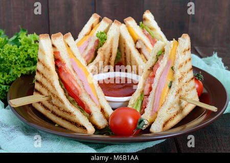 Club-Sandwiches mit knusprigem Toast, Wurst, Käse, Tomaten, Grüns. Traditionelle amerikanische Snack. Stockfoto