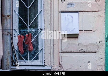 Rote Socken trocken auf Eisen verjähren Fenster bei geschälten alte Mauer mit großen Hausnummer Stockfoto