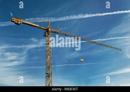 Tall yellow arbeiten Kran auf blauen bewölkten Himmel Hintergrund Stockfoto