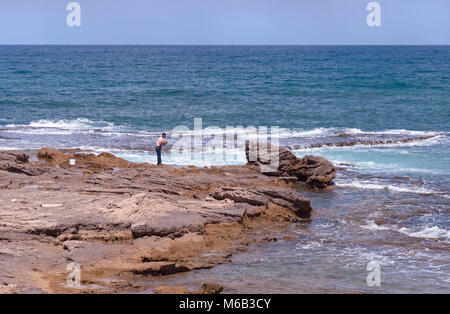 Einsame surf Fischer auf dem Felsen in Cäsarea am Mittelmeer Stockfoto