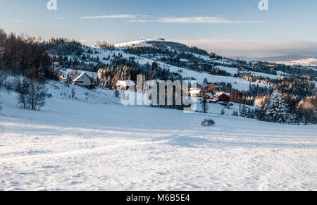 Schöne landschaft von winter Schlesischen Beskiden mit streusiedlung von Ochodzita Koniakow Dorf, Hügel, Schnee und blauer Himmel mit Wolken in Po Stockfoto