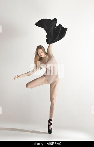Junge schöne Tänzerin in beige Badeanzug tanzend auf grauem Hintergrund Stockfoto