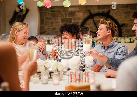 Freunde sind das Toasten Gläser zwischen sich an ihrem Tisch auf einer Geburtstagsparty. Stockfoto