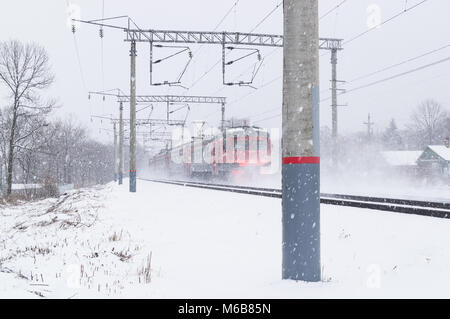 Der Passagier russischen Suburban elektrische Zug bewegt sich bei einem Blizzard im Winter entlang den Schienen des verschneiten Bahn Stockfoto