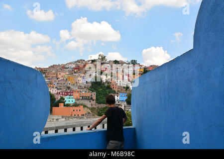 Junger Mann über das bunte Stadtbild von Guanajuato, Mexiko suchen, von einem blau lackiert, seltsam geformte Balkon. Stockfoto