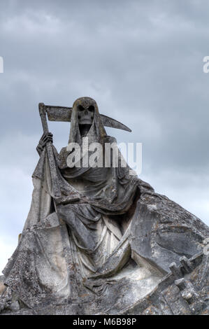 Der Tod personifiziert als Skelett mit Umhang und Sense dieses Bild der verwitterte Skulptur auf dem Friedhof getroffen wurde. Stockfoto