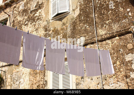 Malerische Wäscheleine mit weißem Leinen hängen in den alten Straßen der historischen Altstadt von Dubrovnik in Kroatien, Europa zu trocknen. Stockfoto