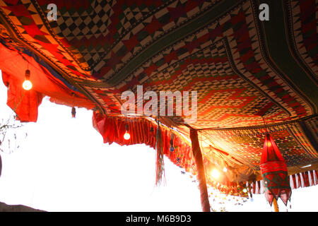 Traditionelle wüste Zelt aus bunt gemusterten ethnische Gewebe auf Holzpfähle, mit Lichtern und anderen Gadgets, Rajastan, Indien eingerichtet. Stockfoto