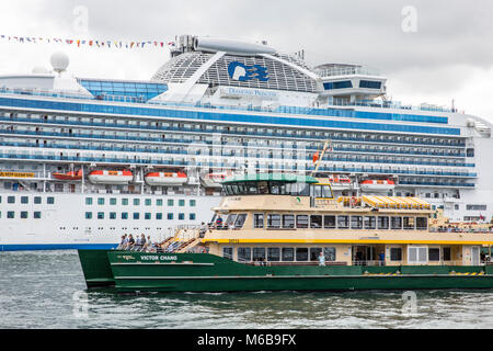 Die Sydney-Fähre MV Victor Chang passiert das Kreuzfahrtschiff Diamond Princess, das am Circular Quay, Sydney, festgemacht ist Stockfoto