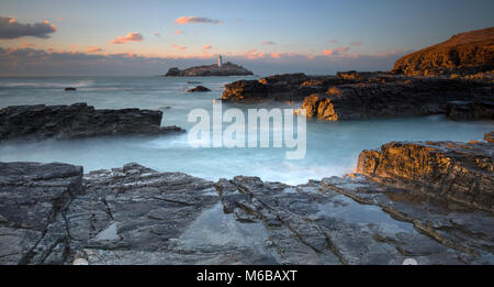 Sonnenuntergang über godrevy Godrevy Leuchtturm auf der Insel in der Bucht von St Ives mit dem Strand und Felsen im Vordergrund, Cornwall Stockfoto