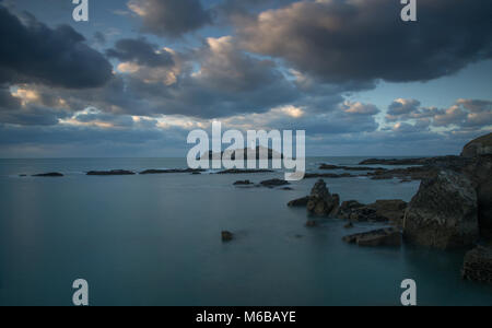 Sonnenuntergang über godrevy Godrevy Leuchtturm auf der Insel in der Bucht von St Ives mit dem Strand und Felsen im Vordergrund, Cornwall Stockfoto