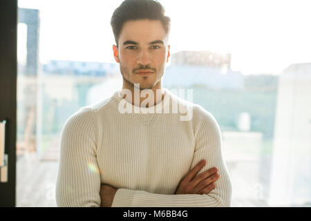 Vordere Porträt der jungen gutaussehenden Mann mit verschränkten Armen Stockfoto