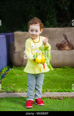 Adorable kleinkind Mädchen in einem Garten mit Zitronen Obst in Ihrer Hand Stockfoto