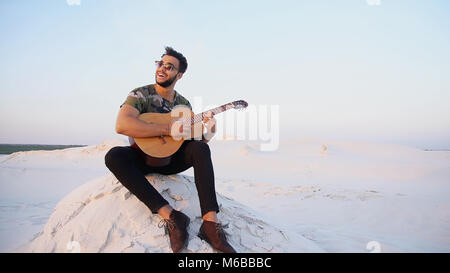 Schönen Arabischen jungen Mann passt die Gitarre, sitzt auf einem Hügel in Mi Stockfoto