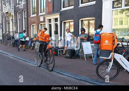 AMSTERDAM, NIEDERLANDE, 9. Juli 2017: Uber isst, und Thuisbezorgd Deliveroo Lebensmittel Kuriere in Amsterdam, Niederlande warten. Fahrrad Essen Lieferung ist po Stockfoto
