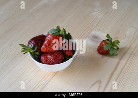 Erdbeeren in einem weißen Teller auf einem hölzernen Hintergrund Stockfoto