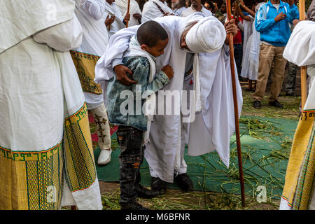 Eine Äthiopische Orthodoxe Priester sieht nach einem Jungen während Timkat (Epiphanie) Feiern im Kidist Mariam Kirche, Addis Abeba, Äthiopien Stockfoto