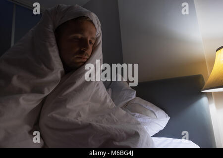 Junger Mann, der durch das Fenster am Morgen. Er steht früh auf Stockfoto