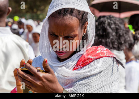 Eine äthiopische Frau Suchen mit Sorge auf Ihr Mobiltelefon, Addis Abeba, Äthiopien Stockfoto