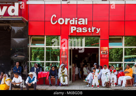 Äthiopische Christen außerhalb eines Cafe während Timkat (Epiphanie) Feiern, Addis Abeba, Äthiopien Sitzen Stockfoto