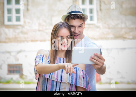 Junge touristische Mann und Frau gemeinsam an digitalen tablet Gerät und auf der Suche nach dem nächsten Reiseziel zu besuchen Stockfoto