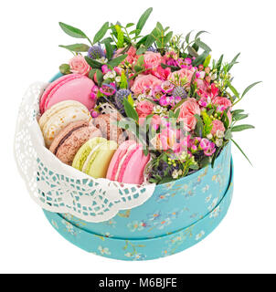 Süße Makronen in Geschenkbox und Blumen auf weißem Hintergrund. Stockfoto