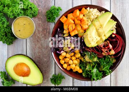 Buddha Schüssel mit Quinoa, Avocado, Kichererbsen, Gemüse auf einem Holz Hintergrund, gesunde Ernährung Konzept. Overhead Szene. Stockfoto