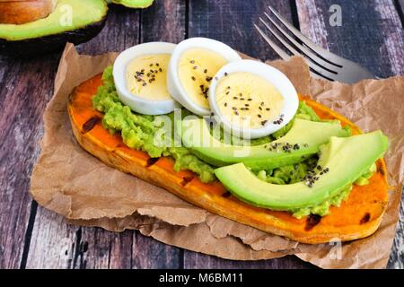 Süßkartoffel-Toast mit Avocado, Eier und Chia Samen. Tabelle Szene mit einem hölzernen Hintergrund. Stockfoto