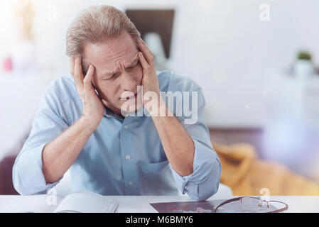 Müde freudlos Mann leidet unter der Kopfschmerzen. Stockfoto