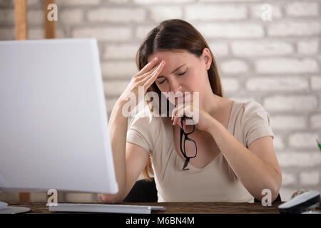 Junge Geschäftsfrau Kopfschmerzen Leiden am Arbeitsplatz Stockfoto