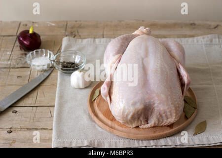 Rohes Huhn auf einem Holzbrett mit Gewürzen und Gemüse. Stockfoto
