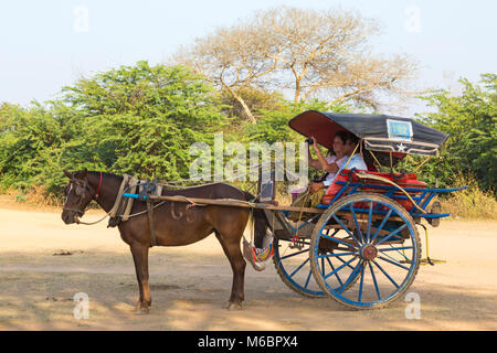 Touristen, die eine Fahrt mit Pferd und Wagen in der Abendsonne in Bagan, Myanmar (Birma), Asien im Februar - angehalten, um ein Foto aufzunehmen Stockfoto