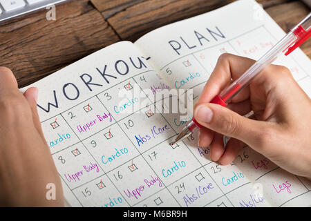 Nahaufnahme einer menschlichen Hand Workout Plan auf Notebook Stockfoto