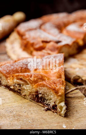 Nahaufnahme von einem Stück ensaimada, ein Gebäck, das typisch für Mallorca, Spanien, mit Schokolade gefüllt, auf einem rustikalen Holztisch Stockfoto