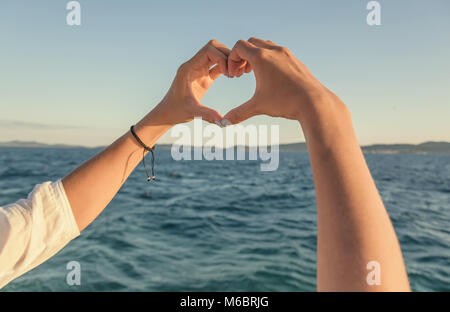 Hände in der Form von Herzen vor dem Hintergrund des Meeres. Stockfoto