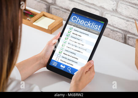Nahaufnahme einer Geschäftsfrau Füllung Checkliste Formular auf Digital Tablet über Schreibtisch Stockfoto