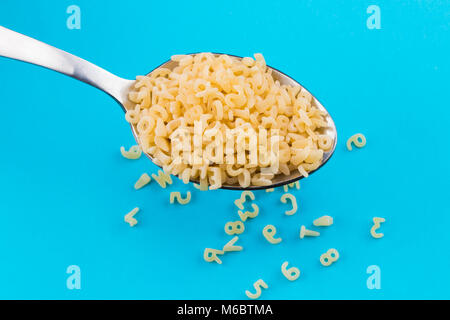 Alphabet Nudeln in Löffel auf blauem Hintergrund. Stockfoto