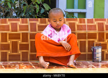 Junge Anfängernonne, die im Februar in Aung Myae Oo Monastic Free Education School, Sagaing, Mandalay, Myanmar (Birma), Asien auf dem Sitz sitzt Stockfoto