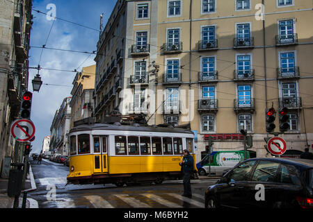 Lissabon, Portugal - 28. Januar 2011: Ein Fußgänger geht vor einer Nr. 12 öffentliche Straßenbahn auf den Straßen der Alfama Viertel, die Altstadt o Stockfoto