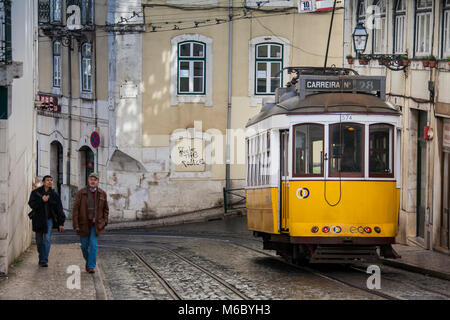 Lissabon, Portugal - 28. Januar 2011: Ein Fußgänger geht vor einem Nr. 28 öffentliche Straßenbahn auf den Straßen der Alfama Viertel, die Altstadt o Stockfoto