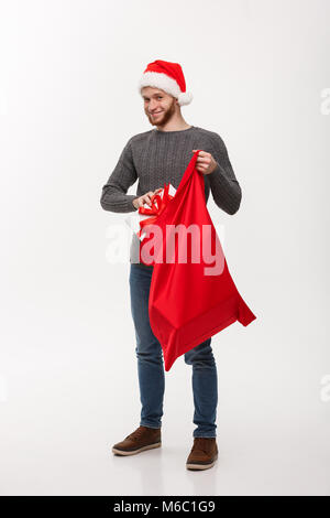 Weihnachten Konzept - Junge glücklich Bart Mann begeistern mit großen in santa Tasche. Stockfoto