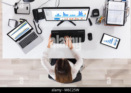 Hohe Betrachtungswinkel und einer jungen Unternehmerin Sitzen auf Stuhl Analyse von Graphen auf dem Computer Stockfoto