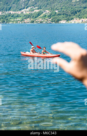 Der Lago d'Orta, Italien, 12. August 2016: eine Hand scheint zu sein, packte ein Kanu mit zwei ältere Menschen paddeln auf den Ortasee - Lago d'Orta in Italien. Stockfoto