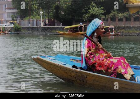 Morgen Blick auf Dal Lake, Srinagar, Kashmir, Indien. Ein Mädchen Rudern eine Bootsfahrt in einem traditionellen Indien Kleidung. Stockfoto